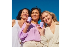 Three women smiling and holding Meno in their hands.